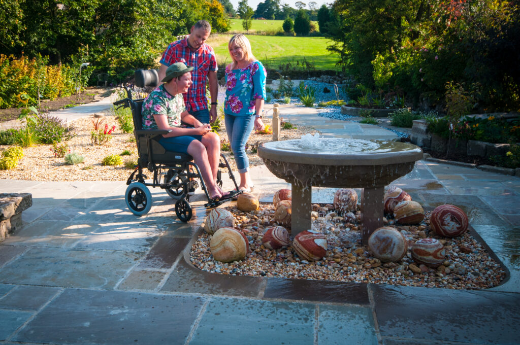 Guests at Croft Bungalow enjoying the water feature in the sensory garden